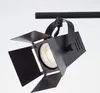 A black spotlight fixture with adjustable barn doors is attached to a black track. Produktbild-Vorschau