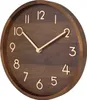 A close-up, angled view of a round wooden wall clock with gold numbers and hands. Voir les images du produit