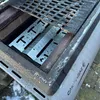 A close-up view of a grill's internal components, showing a metal heat deflector and part of the grill grate. Náhľad obrázku produktu