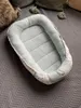 A baby nest is placed on a gray textured surface. Produktbild-Vorschau