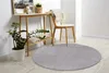 A round gray rug is placed on a light wooden floor in a room with a console table and a chair. Náhled obrázku produktu