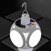 A white and gray solar-powered camping lantern with three illuminated panels is displayed on a dark, textured surface. Anteprima dell’immagine prodotto