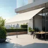 An outdoor patio with a retractable awning, dining table, and chairs, overlooking a city skyline. Náhled obrázku produktu