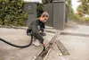 A woman is cleaning a drain with a vacuum cleaner. Anteprima dell’immagine prodotto