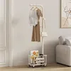 A white coat rack with clothing and a handbag hanging on it, and a storage basket at the bottom. Produktbild-Vorschau