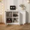 A white cabinet with open doors, displaying books, a radio, and a plant on shelves. A laptop and a vase of flowers are on top. Produktbild-Vorschau