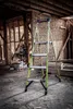 A green Little Giant ladder is set up inside a building under construction. Podgląd zdjęcia produktu