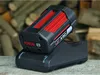 A Bosch battery charger with a battery inserted, placed on a wooden surface with a background of stacked firewood. Produktbild-Vorschau