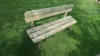 A wooden garden bench sits on a grassy lawn. Produktbild-Vorschau