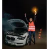 A woman in a reflective vest stands next to a car with its hood open and smoke coming out, holding a glowing orange light stick. Produktbild-Vorschau
