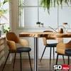 A dining table with chairs in a bright, plant-filled room. Produktbild-Vorschau
