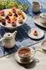 A table setting with tea, pastries, and serving ware. Podgląd zdjęcia produktu