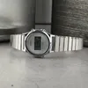 A silver digital watch with a metal band is displayed on a textured gray surface. Produktbild-Vorschau