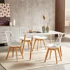 A dining set with four white chairs and a white table is arranged on a rug in a room with a textured gray wall and a decorative cabinet. Náhled obrázku produktu