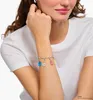 A woman wearing a white t-shirt and a silver charm bracelet with colorful gummy bear charms. Anteprima dell’immagine prodotto
