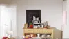 A kitchen or dining area with a sideboard displaying various tableware and decorative items, including a chalkboard with writing. Produktbild-Vorschau