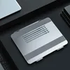 A silver laptop stand is shown on a black surface, with a portion of a laptop visible in the upper left corner. Náhled obrázku produktu