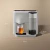 A close-up shot of a modern white tea machine, with a glass of tea and its water reservoir visible. Dimensions are marked with white lines and text. Produktbild-Vorschau