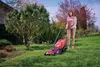 A woman is mowing the lawn with an electric lawnmower in a garden. Náhľad obrázku produktu