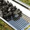 A close-up view of charcoal briquettes piled on a stainless steel grill grate. Produktbild-Vorschau