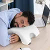 A man is sleeping on a pillow on a desk with a laptop and a lamp in the background. Anteprima dell’immagine prodotto