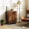 A wooden cabinet with wheels is placed next to a brown leather armchair and a floor lamp. Podgląd zdjęcia produktu