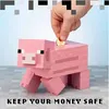 A hand is inserting a coin into a pink Minecraft pig piggy bank. Podgląd zdjęcia produktu