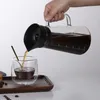 A hand is pouring coffee from a glass carafe into a glass cup. Náhled obrázku produktu
