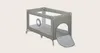 A grey and beige travel crib with a slide-out mat. Produktbild-Vorschau