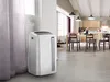 A portable air conditioner is placed in a modern living room/kitchen area. Produktbild-Vorschau