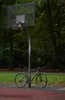 A green gravel e-bike is parked next to a basketball hoop in a park setting. Produktbild-Vorschau