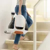 A person is carrying a white and copper Uwant fabric stain remover up a carpeted staircase. Podgląd zdjęcia produktu