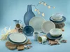 A collection of ceramic dishes and mugs arranged on a light blue background. Náhľad obrázku produktu