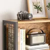 A close-up view of a rustic wooden bookshelf with books, a camera, and a vintage radio. Anteprima dell’immagine prodotto