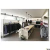 A retail store display featuring clothing on racks and a central display table. Produktbild-Vorschau