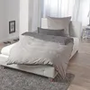A bed with gray bedding in a room. Produktbild-Vorschau