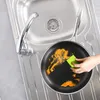 A frying pan is being cleaned in a kitchen sink. Produktbild-Vorschau