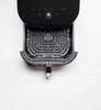 An overhead shot of an open black air fryer with its basket removed, placed on a white marble surface. Produktbild-Vorschau