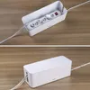 A white cable management box is shown on a wooden surface, with a power strip inside the box in the top image and the box closed in the bottom image. Náhľad obrázku produktu
