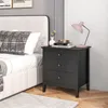 A black nightstand with three drawers is placed next to a bed in a bedroom. Anteprima dell’immagine prodotto