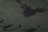 A close-up view of a green blanket with a dark gray stag head pattern. Produktbild-Vorschau