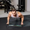 A man is doing push-ups in a gym using a push-up board. Produktbild-Vorschau