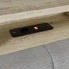 A close-up view of a charging station with USB ports and an orange switch, integrated into a wooden surface, with a gray fabric surface visible below. Voir les images du produit