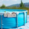 A pool storage basket attached to the side of an above-ground pool, holding a drink, a soccer ball, and a football. Produktbild-Vorschau