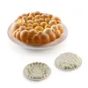 A baked cake with a bubble-like texture sits on a white plate, with two silicone molds of the same texture below it, all on a white background. Anteprima dell’immagine prodotto