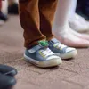 Close-up of children's feet wearing shoes, with a decorative tag on one shoe. Produktbild-Vorschau
