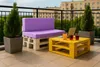 A balcony setting with a pallet sofa and coffee table, decorated with plants and drinks. Produktbild-Vorschau