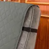 Close-up of a gray quilted chair cover with a black strap and buckle securing it to the armrest of a chair. Anteprima dell’immagine prodotto
