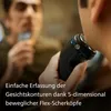 A person is shaving their face with an electric shaver, looking in a mirror. Podgląd zdjęcia produktu