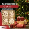 A box of straw stars is shown in front of a decorated Christmas tree with gifts. Produktbild-Vorschau